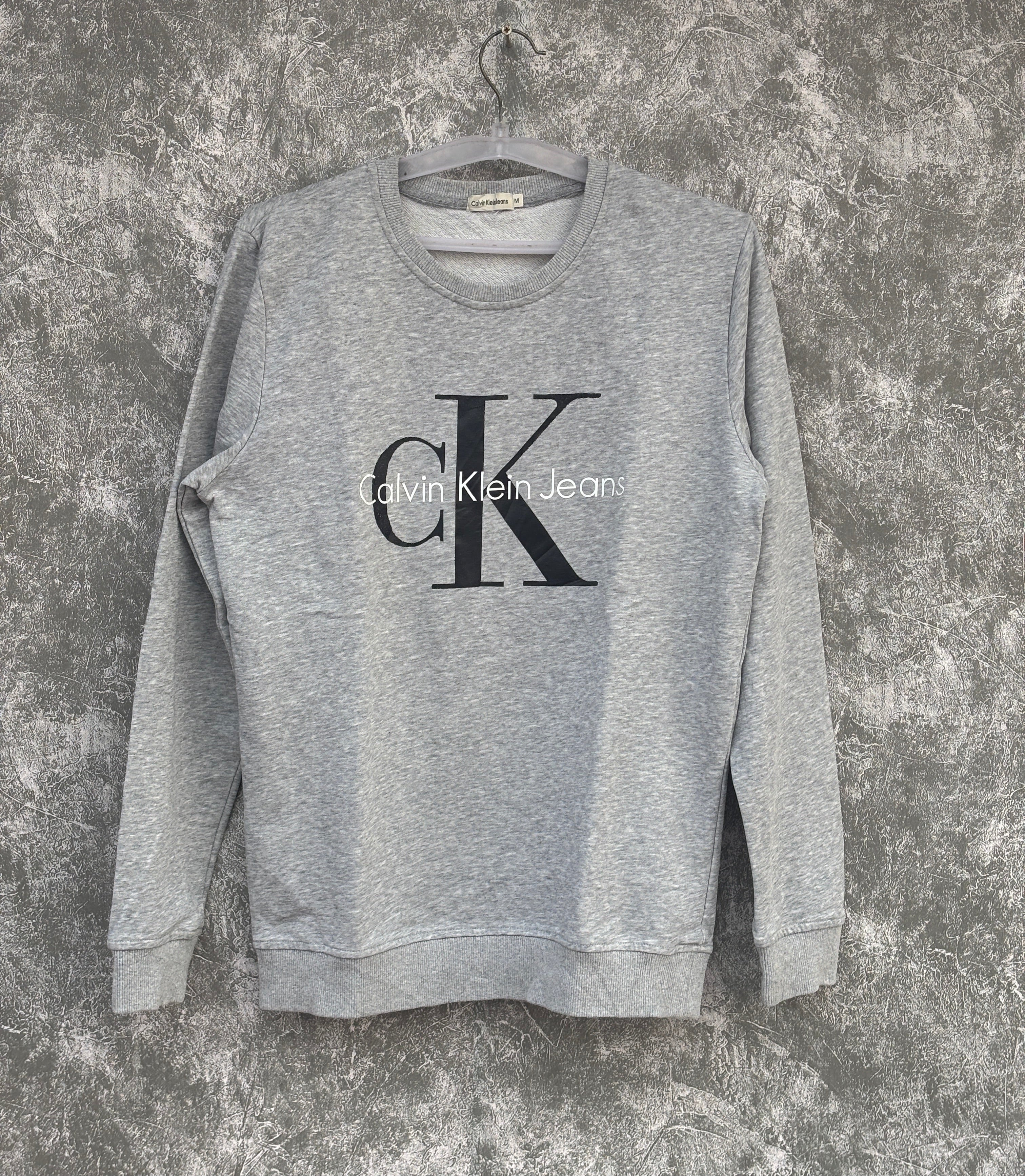 Gray sweatshirt with Calvin Klein logo on a textured surface
